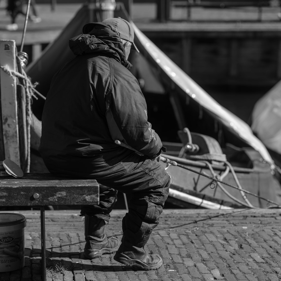 Elderly Croatian fisherman mending fishing nets on a wooden boat